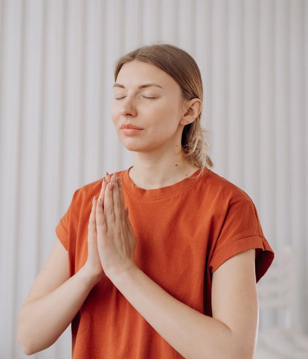Woman practicing a gentle yoga pose in a calm, light-filled room.